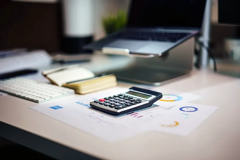 Gros plan sur une calculatrice à côté d'un ordinateur portable