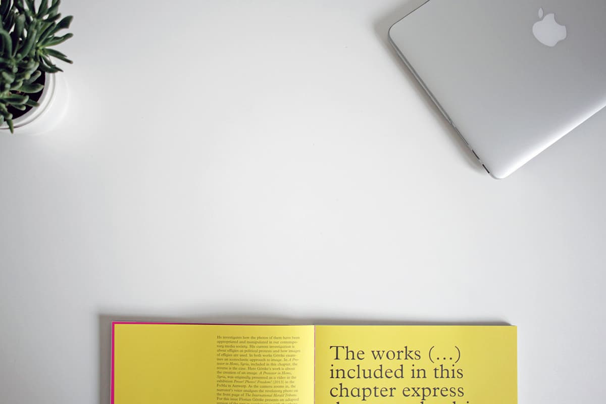 Un espace de travail créatif et épuré avec un ordinateur et des livres, symbolisant une communication visuelle soignée