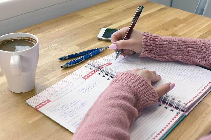 Gros plan sur une personne écrivant des notes brutes, illustrant la récolte d'idées humaines