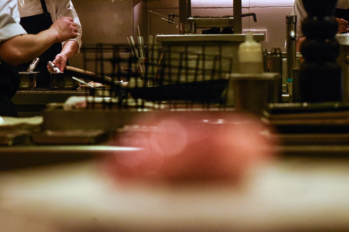 Une équipe de chefs s'affairant dans une cuisine de restaurant très animée, illustrant les coulisses et le savoir-faire