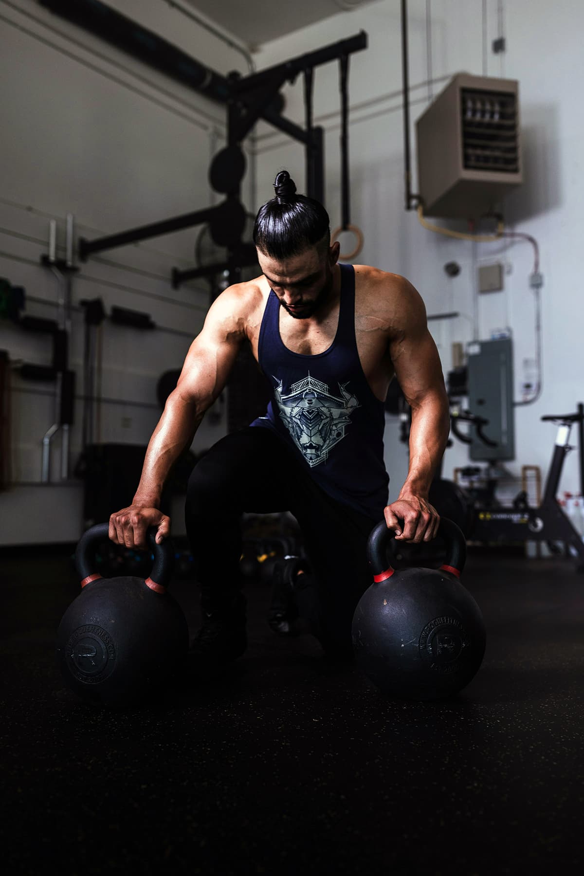 Un athlète tenant de lourdes kettlebells dans une salle de sport sombre, symbolisant l'effort et la discipline
