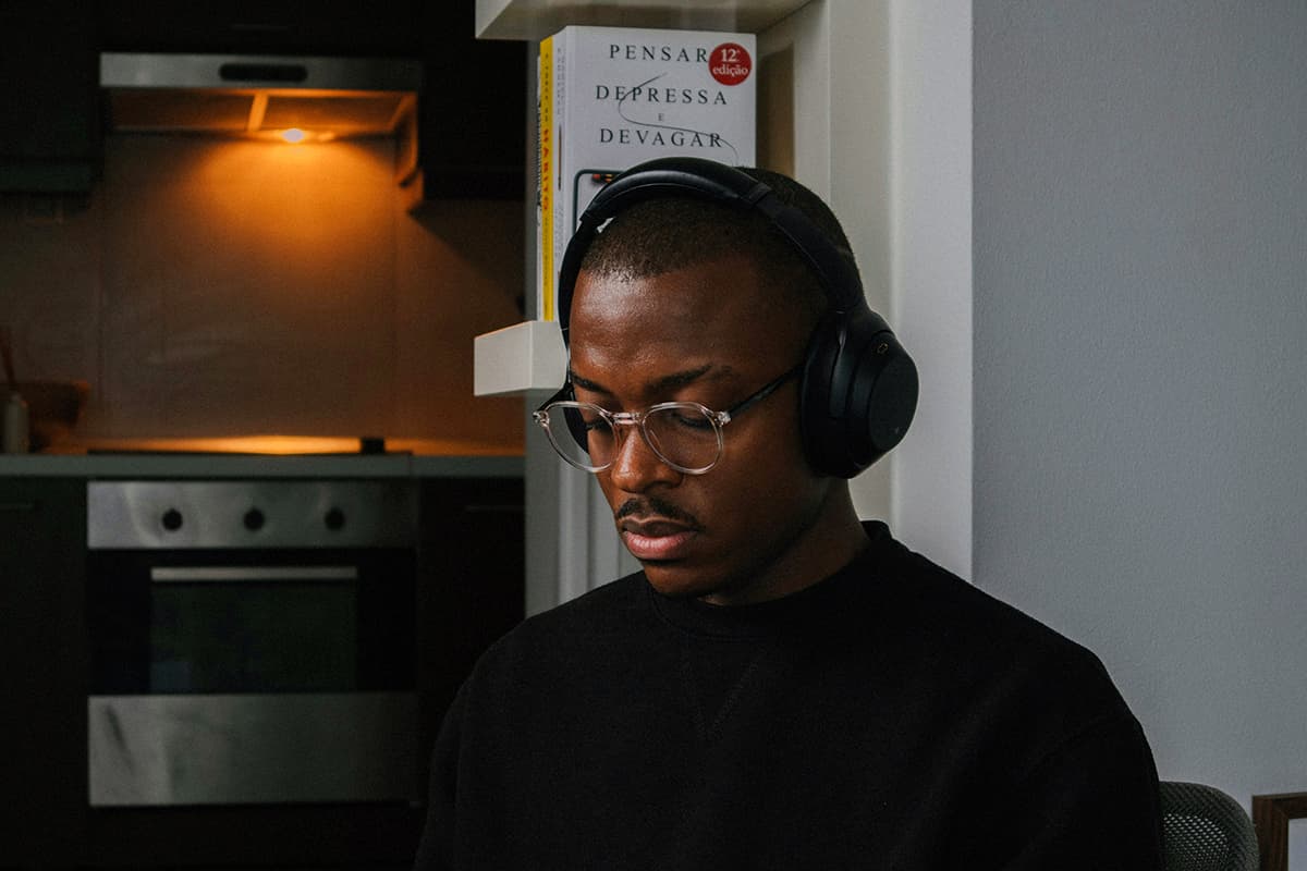 Un homme portant un casque et assis devant un ordinateur portable, les yeux fermés, en pleine méditation ou réflexion profonde
