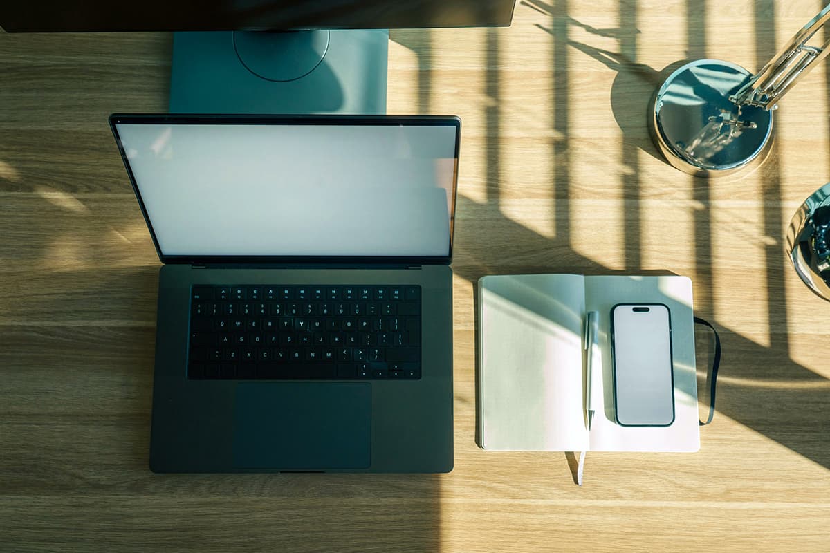 Un espace de travail épuré avec un ordinateur portable et un carnet de notes ouvert