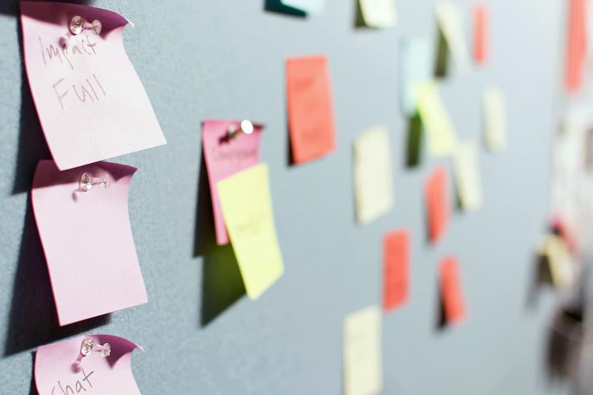 Une personne en train d'organiser des post-its colorés sur un mur pour structurer ses idées
