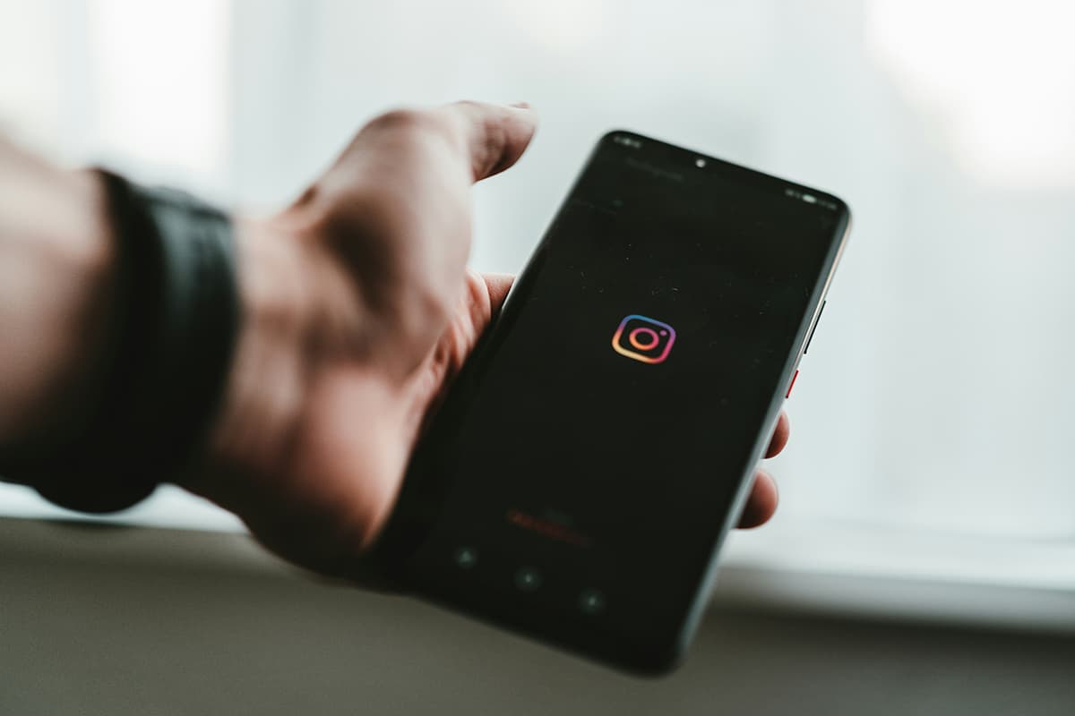 Une personne tenant un smartphone noir dans la pénombre, illustrant le concept d'interactions invisibles du Dark Social
