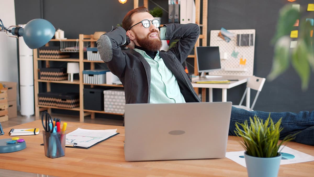 Homme détendu à son bureau ayant réussi à prendre du recul sur ses statistiques