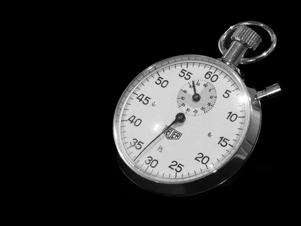 Gros plan sur un chronomètre argenté sur fond noir, symbolisant la mesure du temps