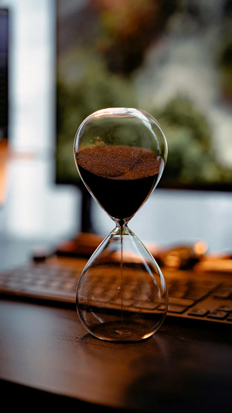 Un sablier sur un bureau illustrant le temps qui passe et l'urgence pour les freelances