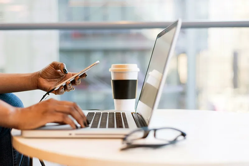 Professionnel gérant sa communication sur ordinateur et smartphone