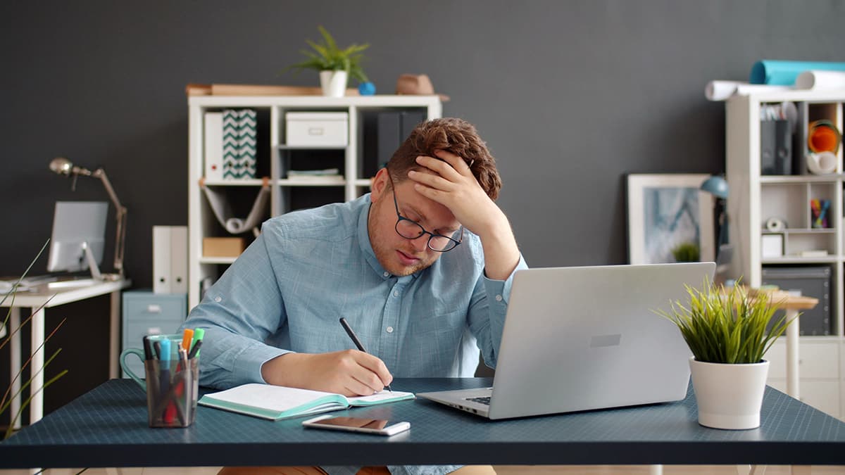 Un homme stressé devant son ordinateur, illustrant le burn-out et la surcharge de travail