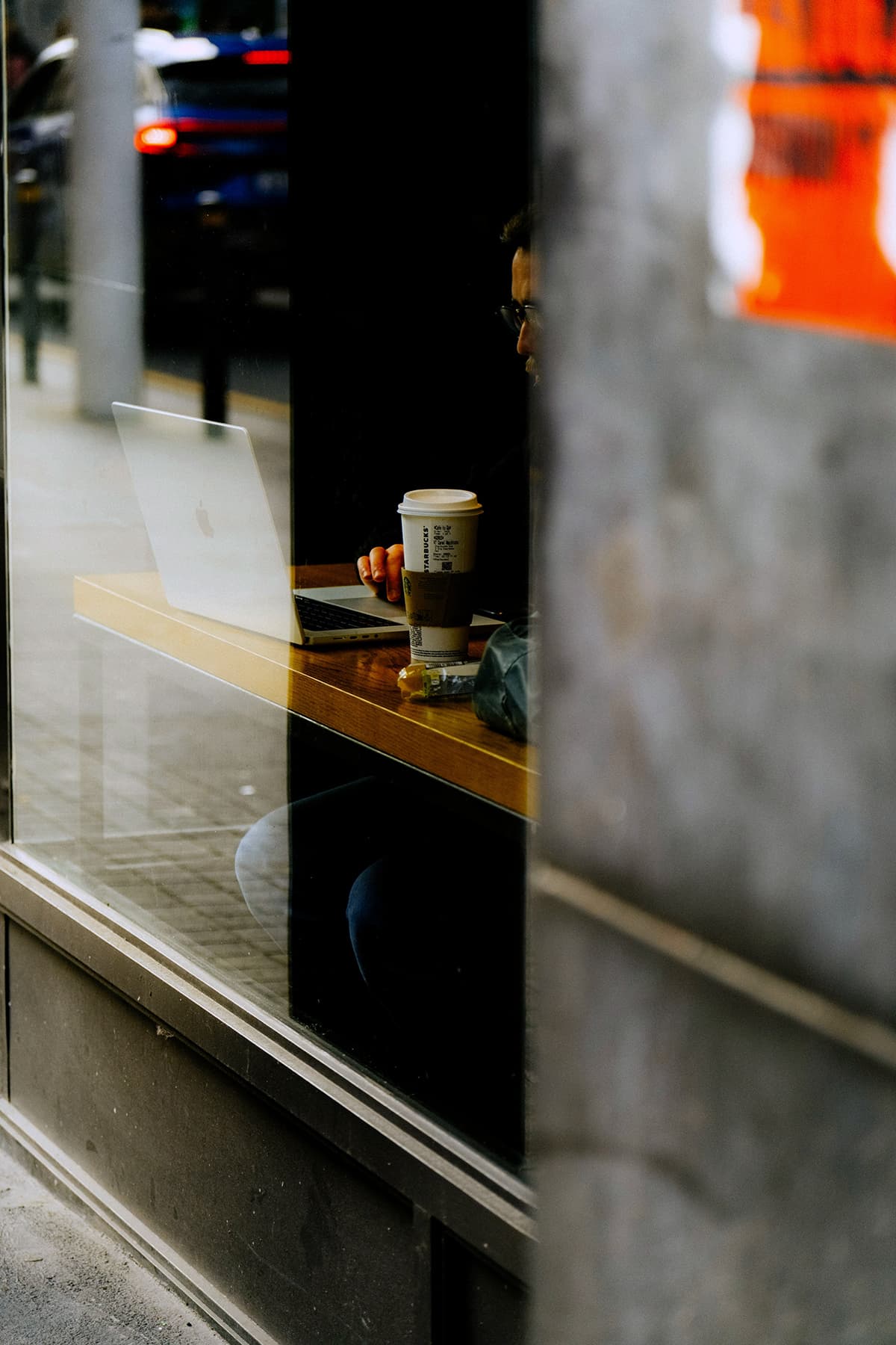 Une personne travaillant sur un ordinateur portable avec une tasse de café dans un café chaleureux, symbolisant le solopreneur rédigeant ses contenus
