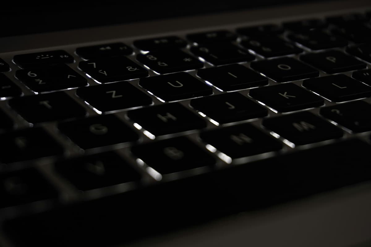 Gros plan sur un clavier d'ordinateur dans la pénombre, symbolisant les critiques anonymes