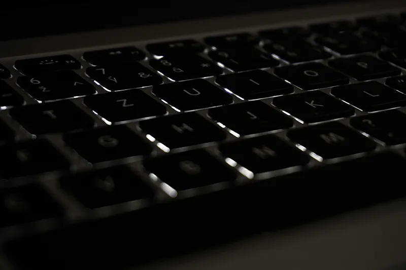 Gros plan sur un clavier d'ordinateur dans la pénombre, symbolisant les critiques anonymes