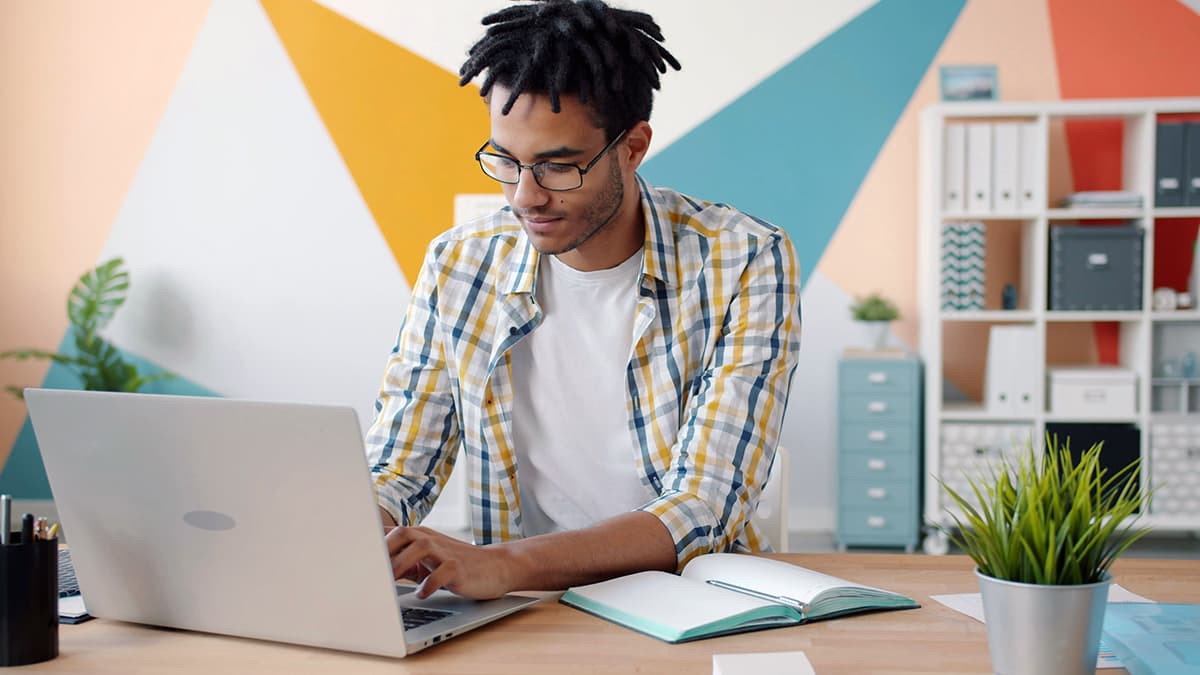 Créateur concentré sur son ordinateur, utilisant la technologie pour optimiser son temps