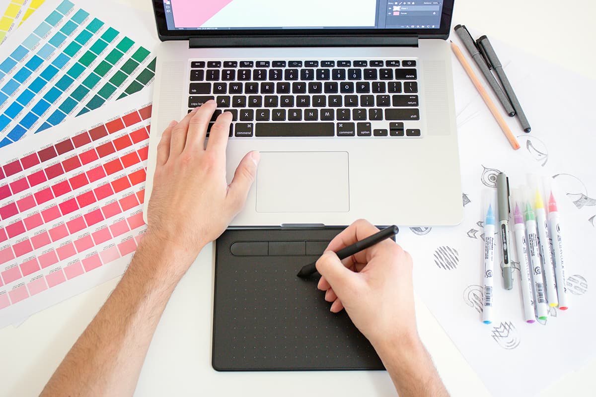 Designer travaillant sur un ordinateur portable avec des outils graphiques