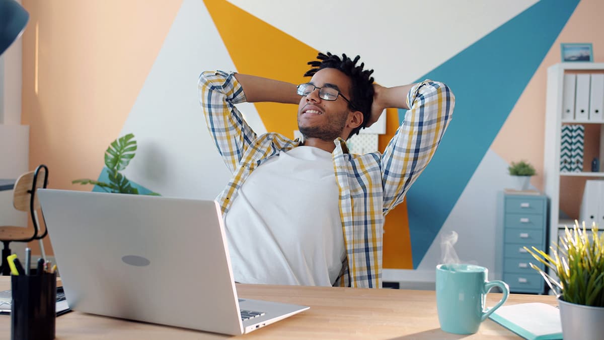 Créateur détendu buvant un café devant son ordinateur, ayant automatisé son design