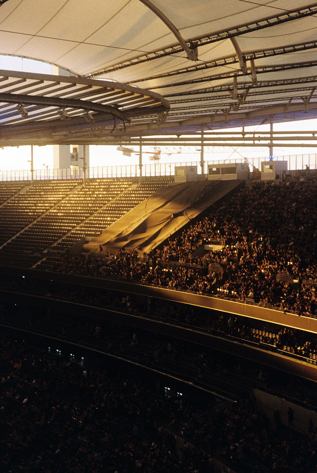 Un stade rempli de spectateurs au coucher du soleil, symbolisant l'engouement pour un grand événement sportif