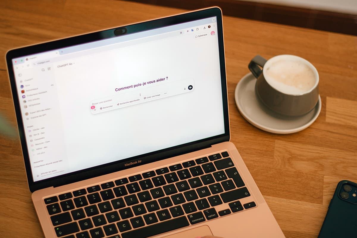 Un ordinateur portable ouvert et une tasse de café sur une table de travail, illustrant la lecture d'une newsletter