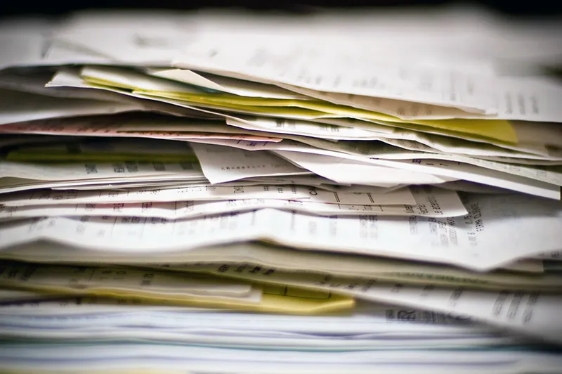 Une personne triant méthodiquement une pile de papiers colorés, illustrant le traitement des tâches par lots