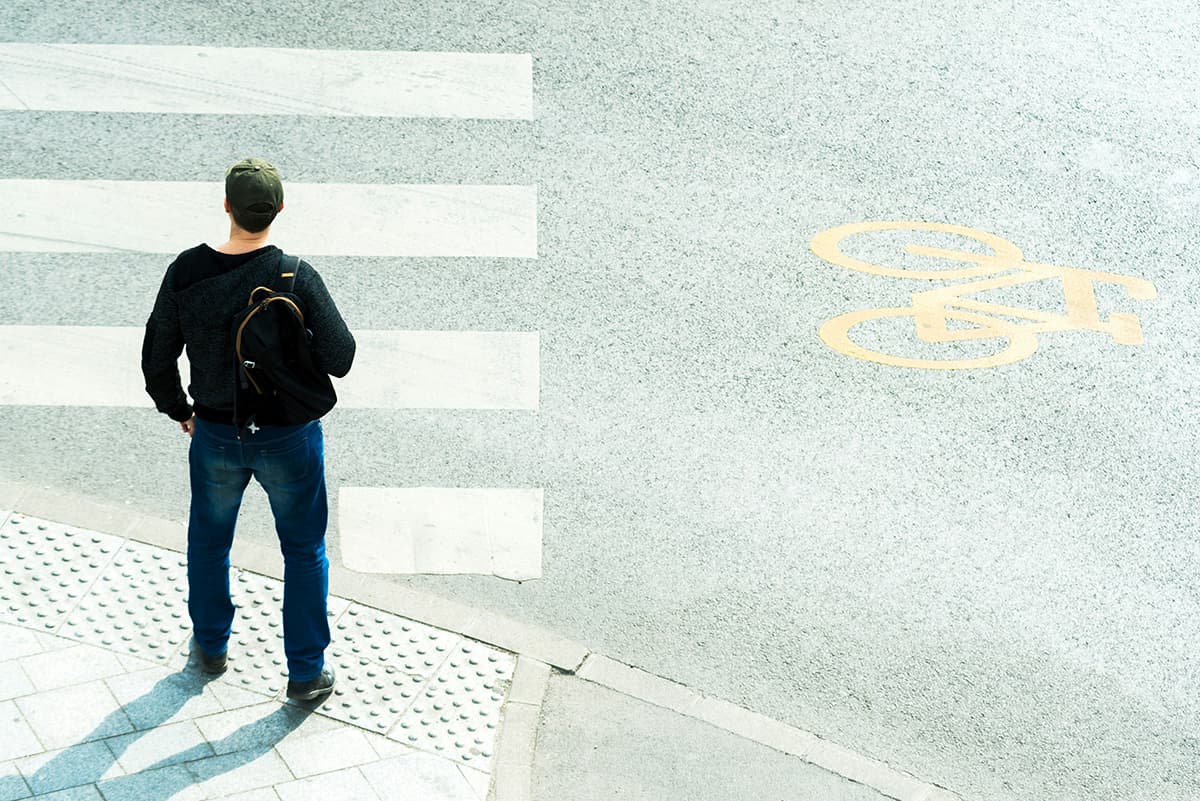 Une personne vue de dos face à un passage piéton à un carrefour, symbolisant la prise de décision et la nouvelle voie à suivre en B2B
