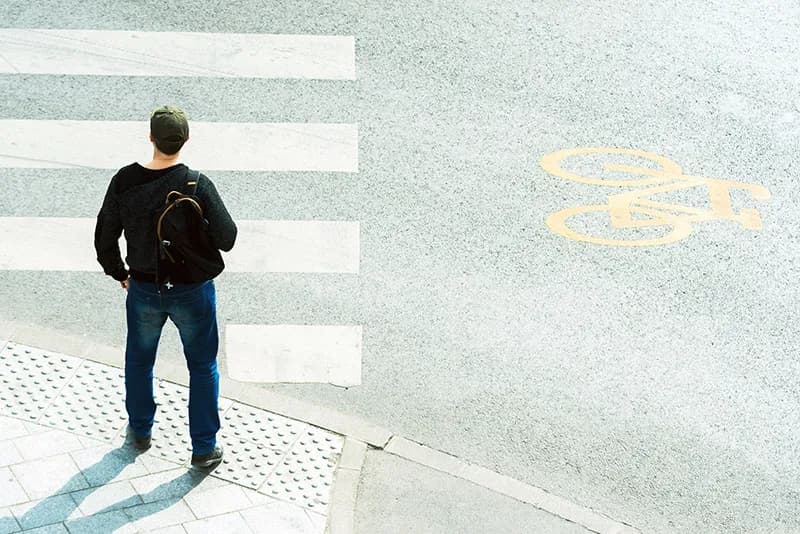 Une personne vue de dos face à un passage piéton à un carrefour, symbolisant la prise de décision et la nouvelle voie à suivre en B2B