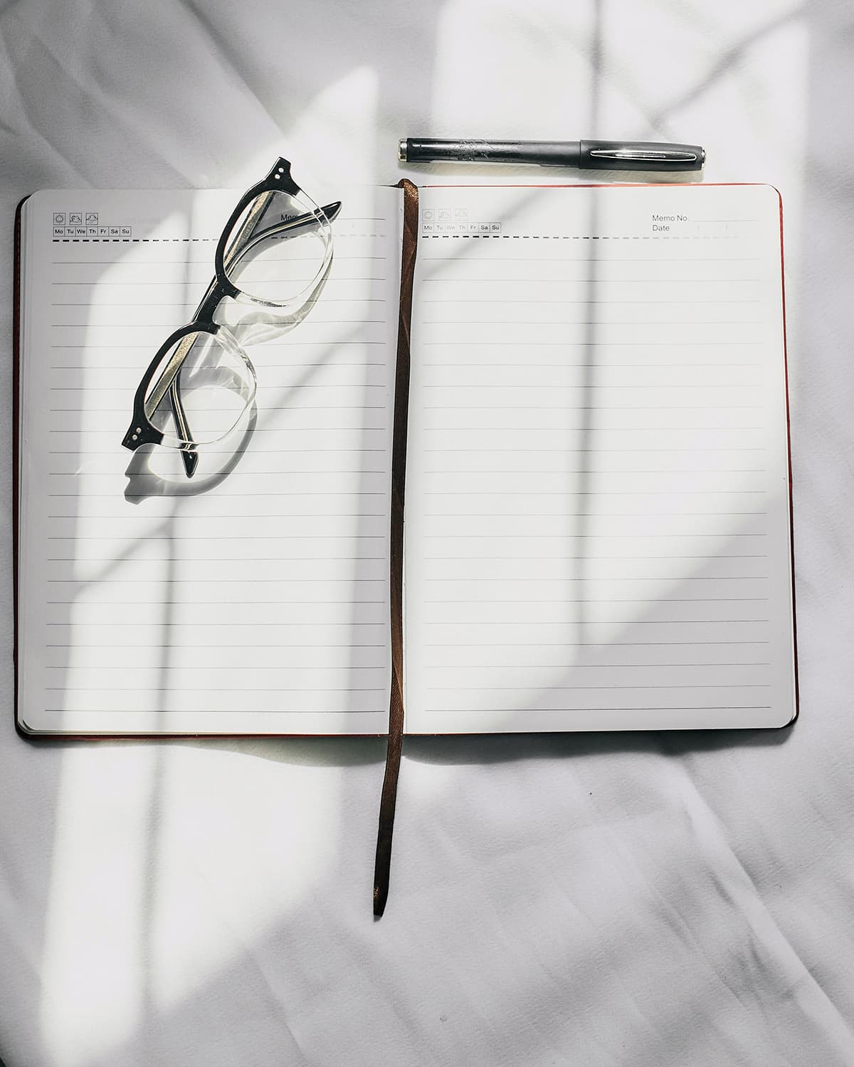 Un carnet de notes ouvert avec un stylo et des lunettes, symbolisant la recherche d'idées brutes