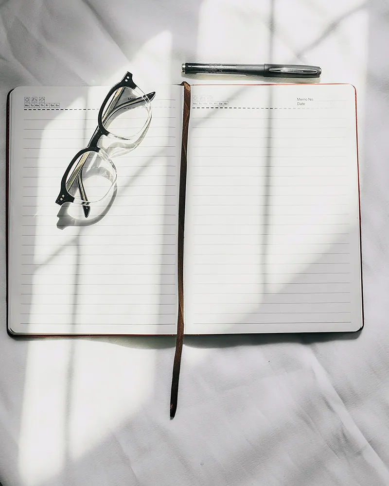 Un carnet de notes ouvert avec un stylo et des lunettes, symbolisant la recherche d'idées brutes