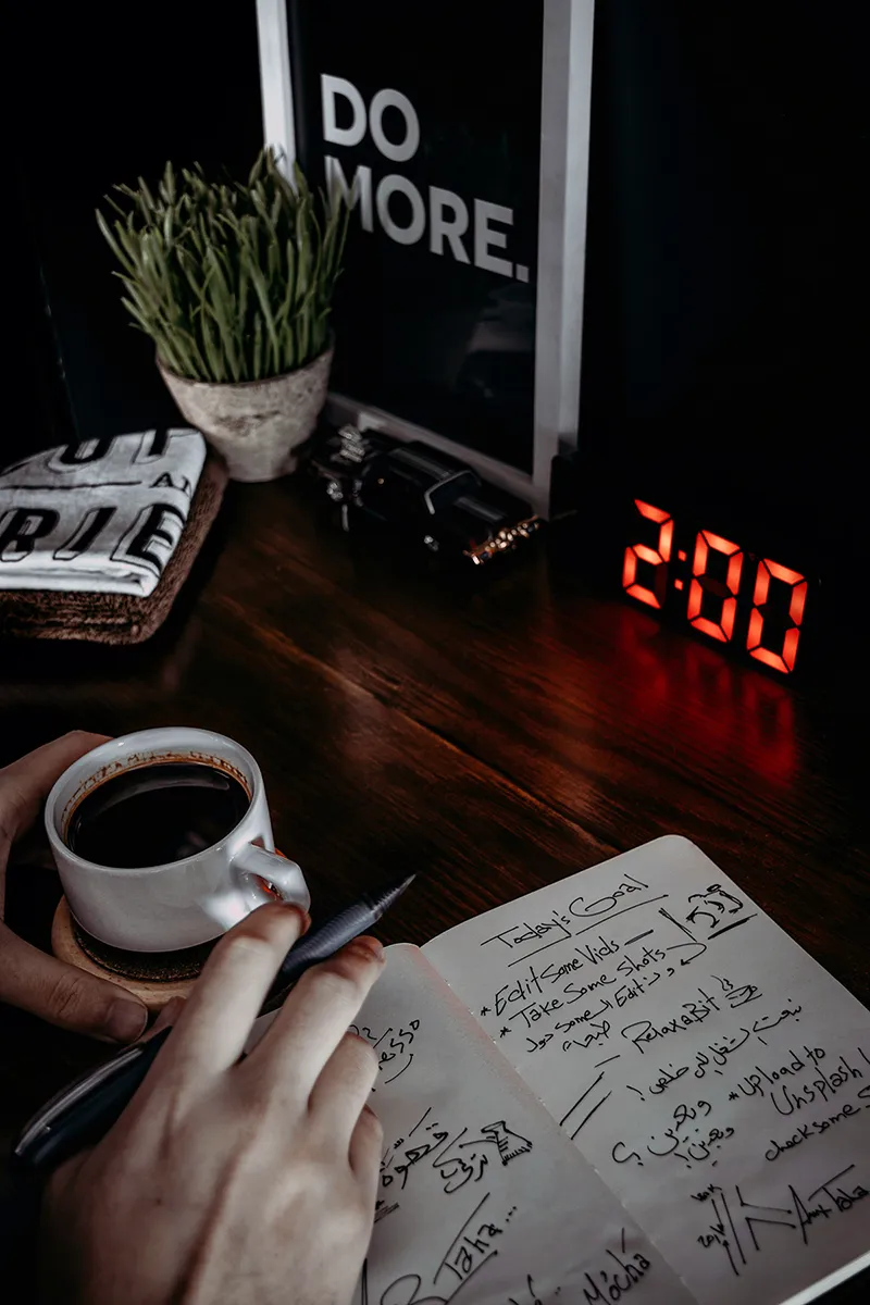 Une personne écrivant dans un carnet à côté d'une horloge, représentant le concept de timeboxing