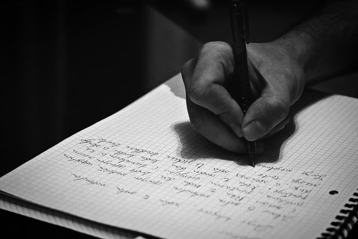 Une personne concentrée en train d'écrire au stylo dans un carnet, symbolisant le Deep Work et l'écriture pure