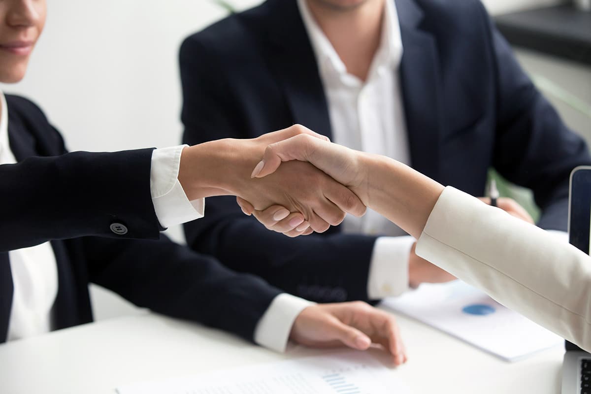 Poignée de main concluant un deal B2B suite à une relance commerciale réussie