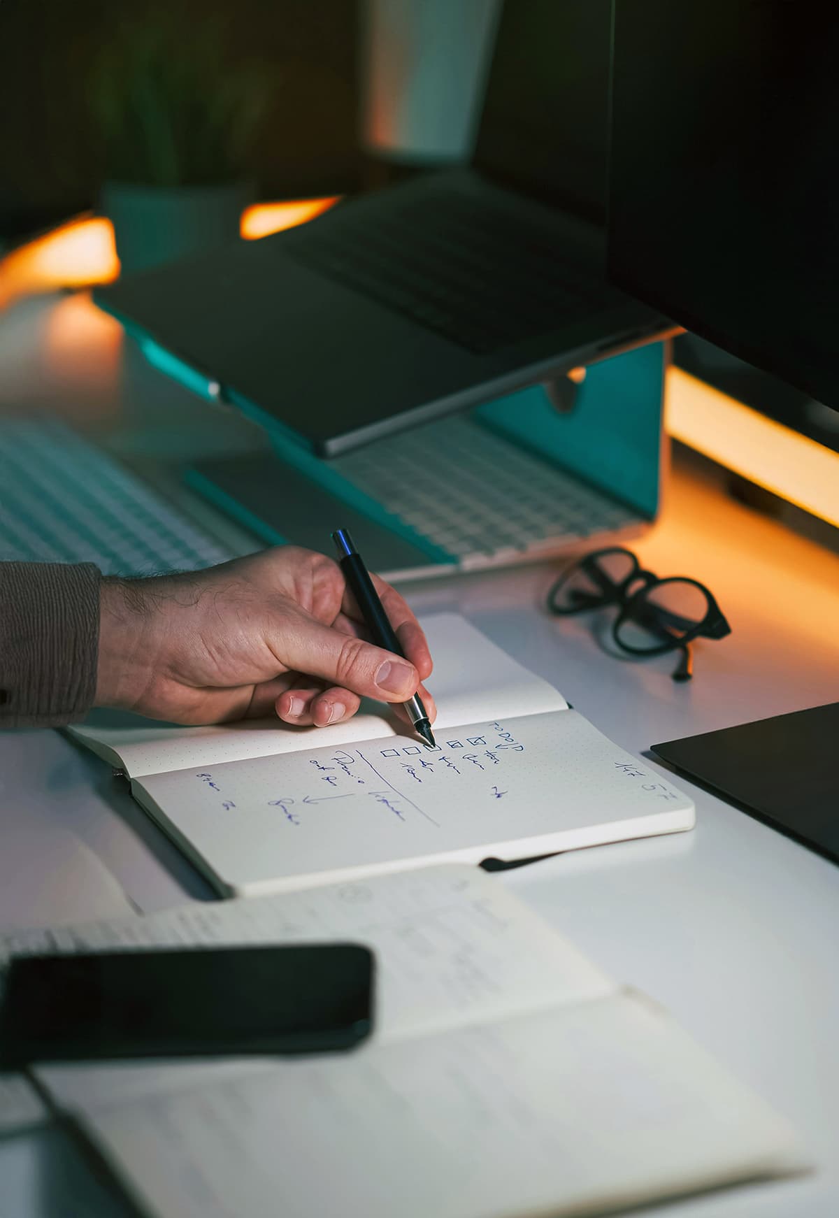 Gros plan sur une main écrivant des notes et une checklist dans un carnet de bord, illustrant le suivi des retours