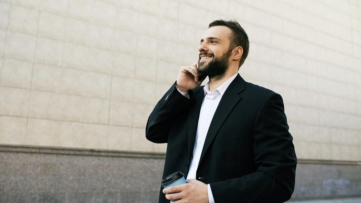 Homme d'affaires en costume riant ouvertement, prouvant que l'émotion a sa place en B2B