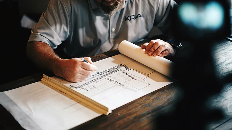Plans d'architecte sur une table, illustrant la structuration algorithmique de la pensée brute