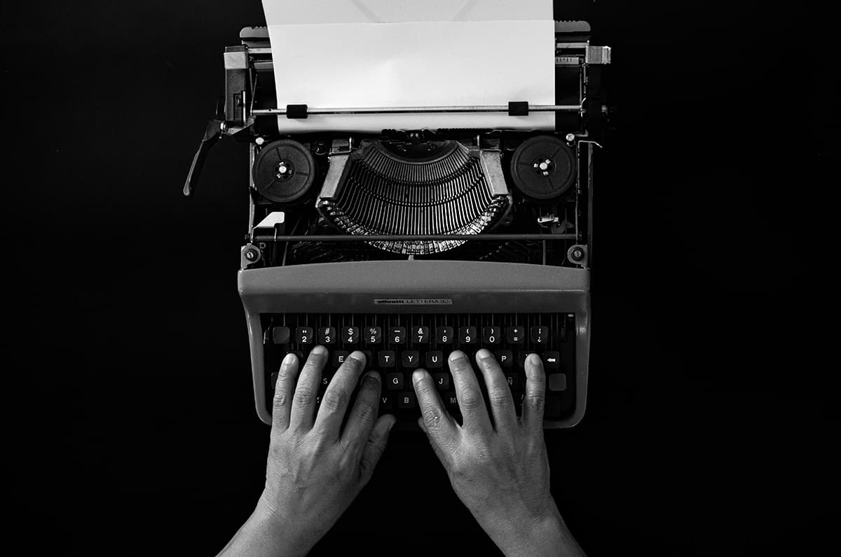 Des mains tapant sur une machine à écrire vintage, symbolisant l'écriture authentique et le contact humain