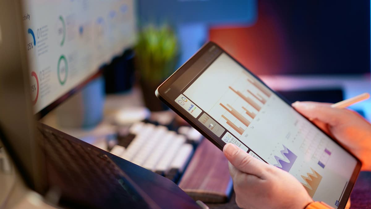 Une personne analyse des statistiques financières sérieuses sur une tablette numérique