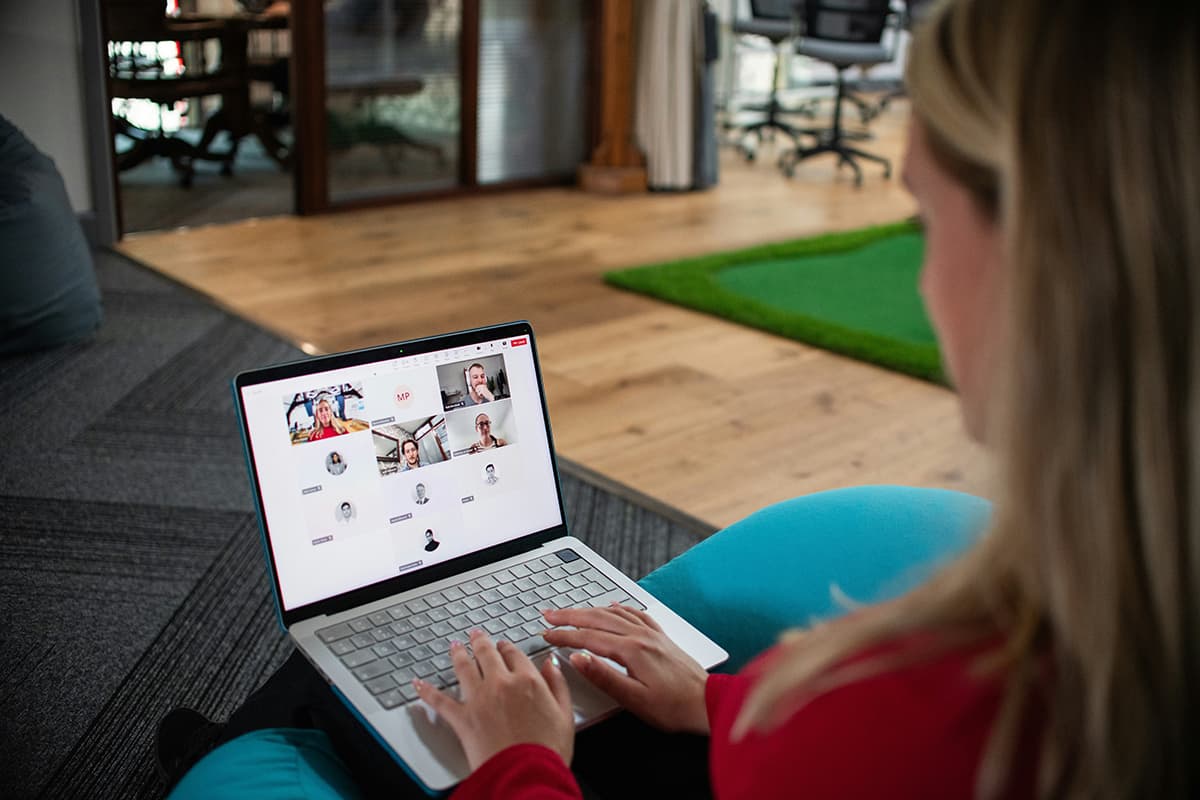 Une femme participant à une visioconférence sur son ordinateur, illustrant le format webinaire