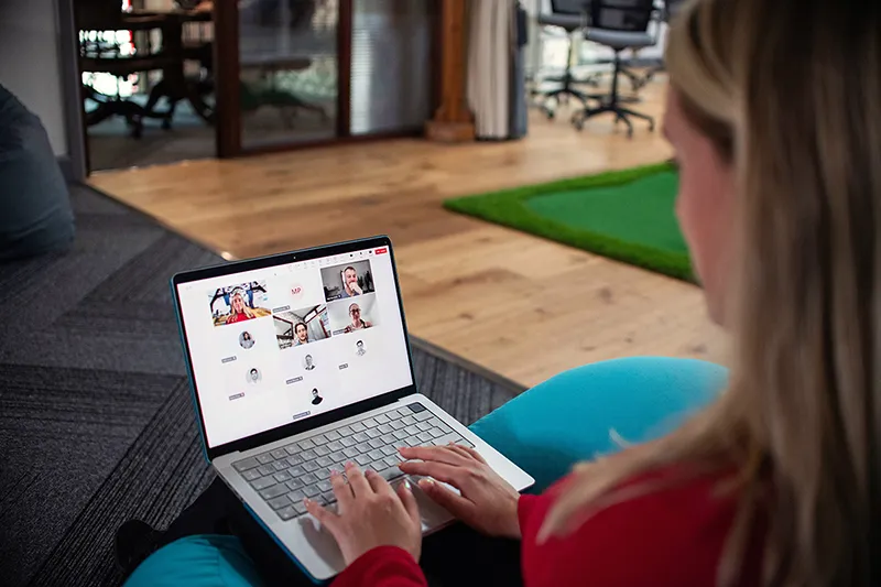 Une femme participant à une visioconférence sur son ordinateur, illustrant le format webinaire